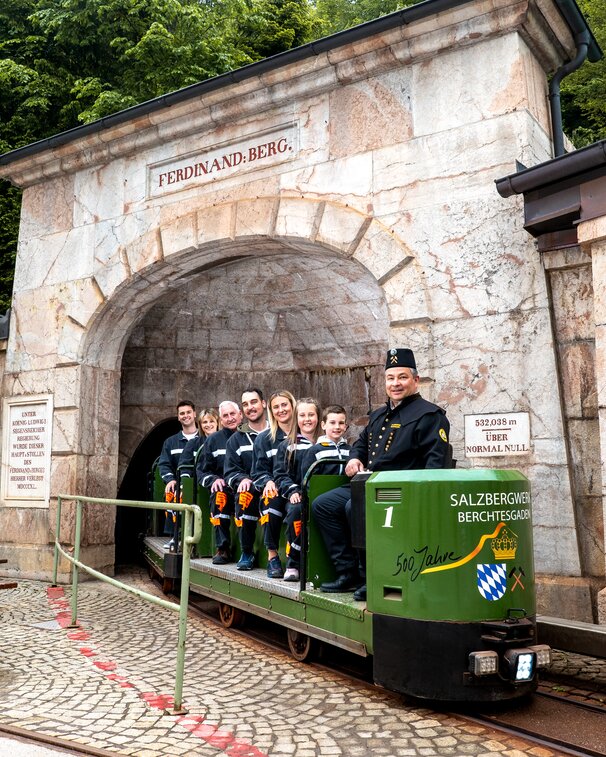 Bergmann mit Gästen auf Besucherbahn im Ausfahrtsstollen des Salzbergwerks